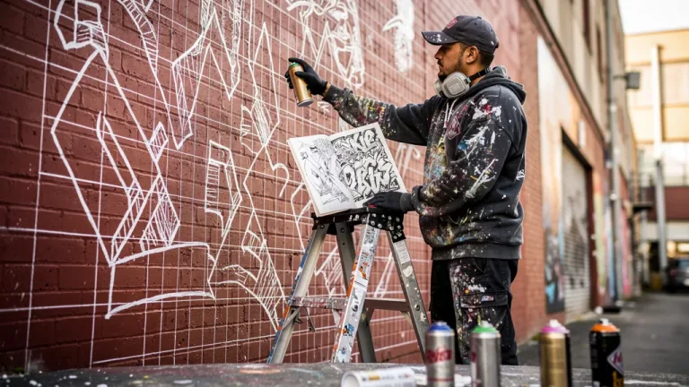 Graffiti artist applying grid scaling technique to a large brick wall from a blackbook design.