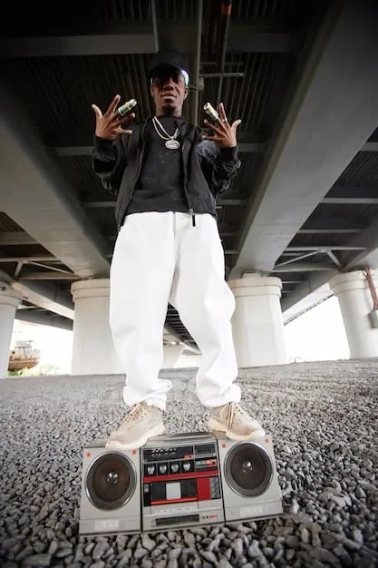 A vintage photograph of a 90s hip-hop artist, possibly wearing an oversized FUBU jersey and baggy jeans, with a gold chain, performing on stage with a microphone.