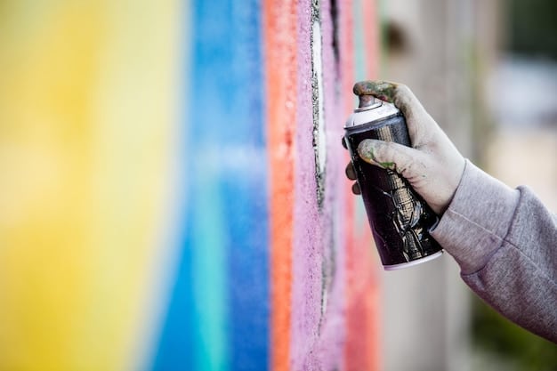 A close-up of a graffiti artist's hand spraying paint from an Ironlak can onto a brick wall, showcasing rich, unfaded colors.