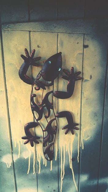 A detailed micro-mural painted on a worn mailbox, depicting tiny fantastical creatures interacting with the mailbox's features, placed on a busy sidewalk.