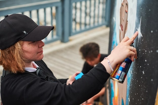 A close-up of a student outlining a complex urban-themed design on a large canvas, demonstrating advanced artistic skills and concentration.