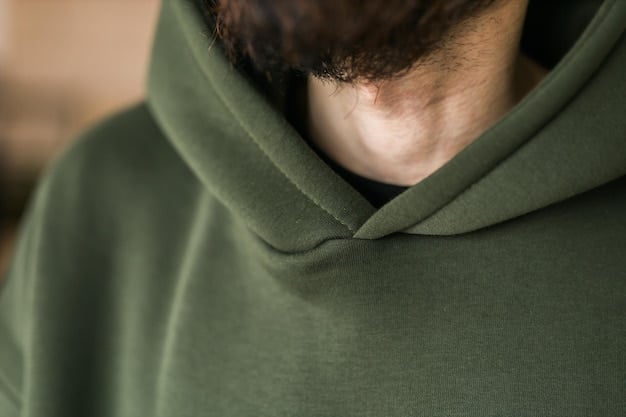A close-up of a sustainably sourced hoodie in a muted earth tone, featuring intricate embroidery inspired by nature. The fabric has a natural, slightly textured appearance, and the lighting highlights its softness.
