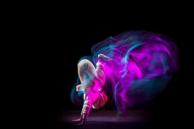 A solo hip hop dancer executing a complex freeze pose on a dimly lit stage, surrounded by wisps of smoke, emphasizing the power and grace of the movement.
