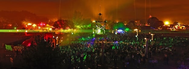 A panoramic view of a packed Rolling Loud festival crowd, with a rap artist performing on stage. The atmosphere is electric, capturing the energy and excitement of the event.