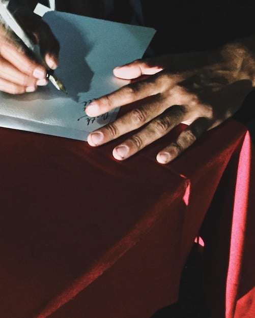 A close-up shot of a rap artist's hands signing a music publishing contract, highlighting the legal documents and the significance of understanding copyright law and its implications. The background should be blurred to focus on the contract and hands.