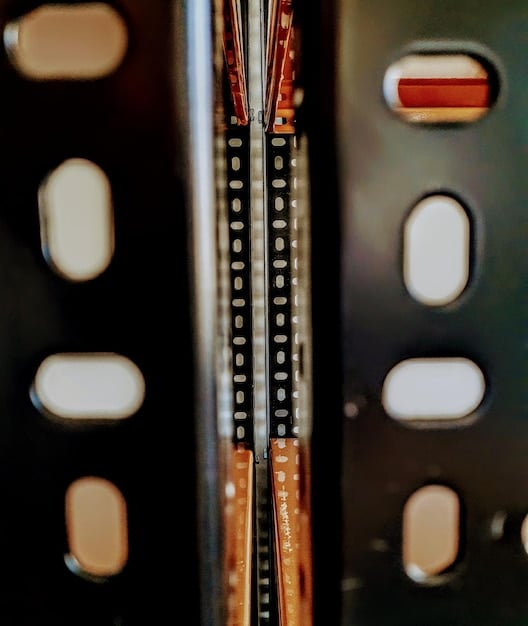 A close-up shot of a modular synthesizer panel with a complex network of patch cables connecting various modules. Knobs are adjusted and buttons are illuminated, showcasing the intricacy of sound manipulation. The focus is on the detail of individual modules and their interconnections.