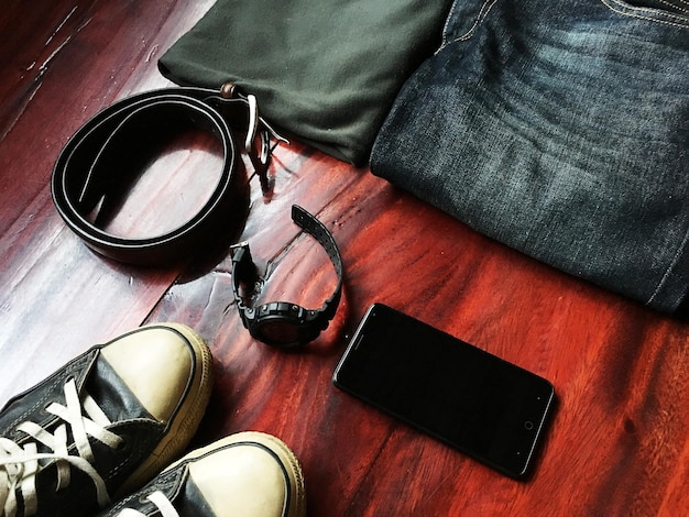 A flat lay of various streetwear accessories including a limited-edition cap, a graphic t-shirt, and a small leather good, all from different collaborations, laid out neatly on a concrete background.