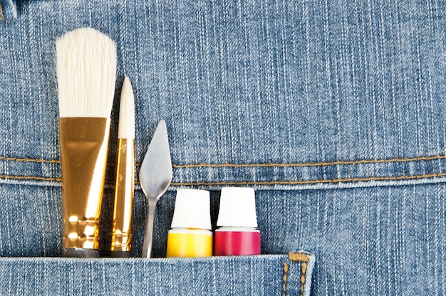 A flat lay of various streetwear customization tools and materials, including fabric paints, brushes, patches, an embroidery hoop, and various threads, all neatly arranged on a work surface, awaiting a creative project.