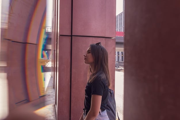 A person in a casual streetwear outfit, wearing a minimalist black backpack with subtle branding, walking down a vibrant city street lined with murals.