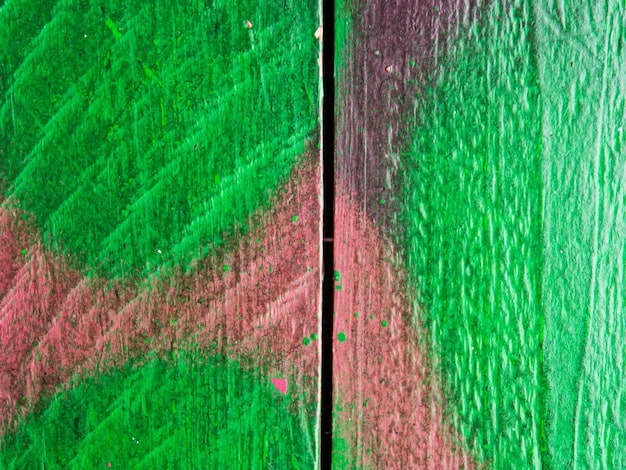 A close-up of a graffiti mural detailing the interaction of red and green spray paint, highlighting texture and layering, with specific small elements in sharp contrast.
