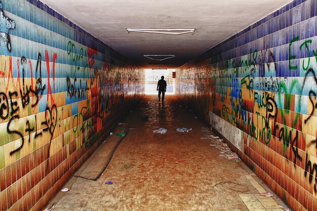 A panoramic view of an urban alleyway covered in a variety of graffiti styles, with one central mural depicting a figure breaking free from chains, symbolizing liberation and hope.