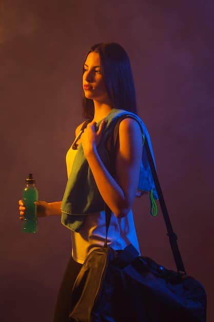 Hip hop dancer holding a stylish branded water bottle, posing confidently backstage at a virtual performance, with studio lighting and a subtle corporate logo in the background.